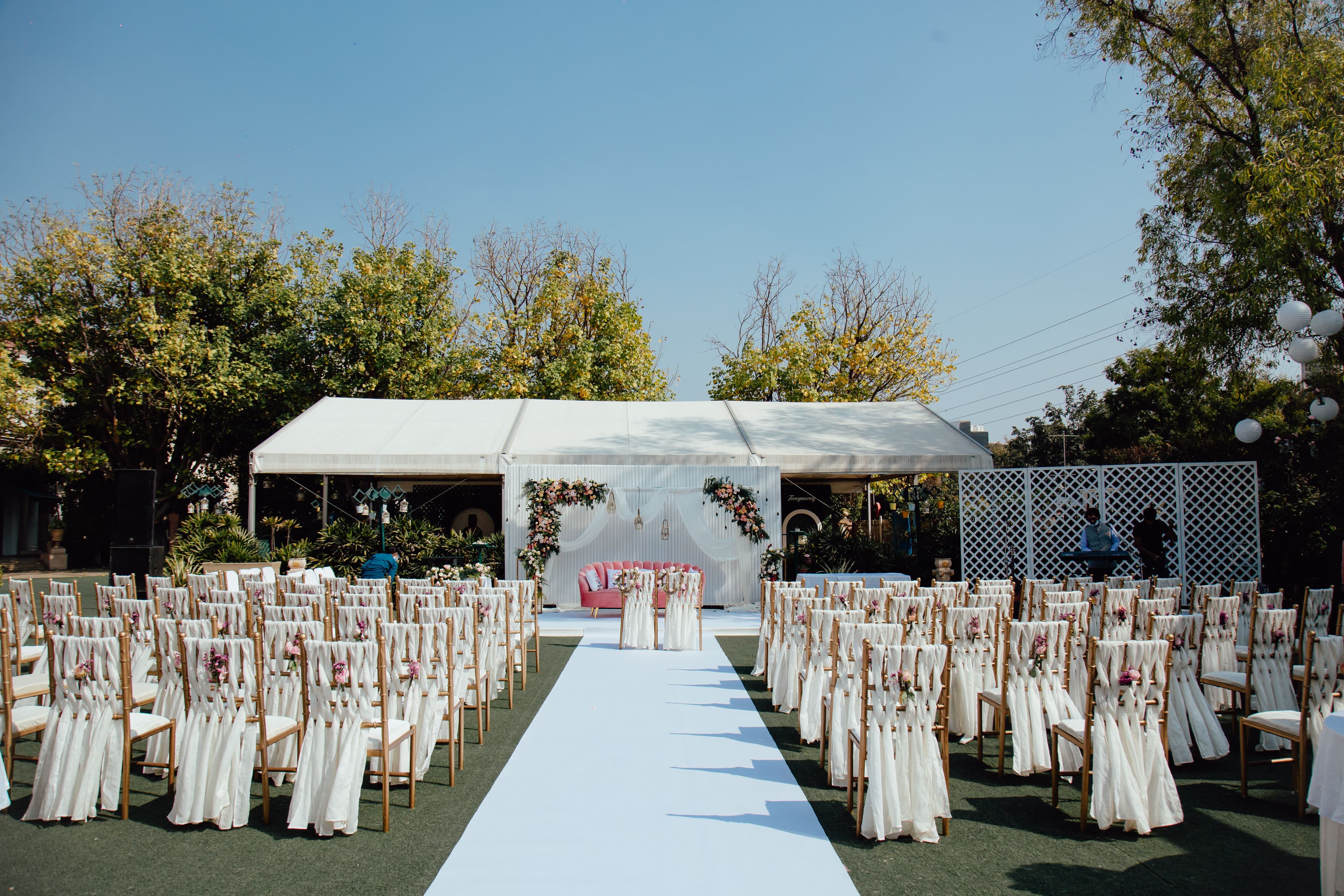 Elegant outdoor wedding ceremony setup with white chairs and floral arch — the kind of event where luxury portable restroom rentals make a real difference